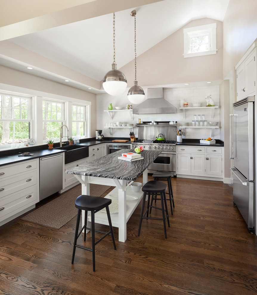 Inspiration for a classic u-shaped kitchen in Portland Maine with a belfast sink, recessed-panel cabinets, white cabinets, white splashback, metro tiled splashback and stainless steel appliances.