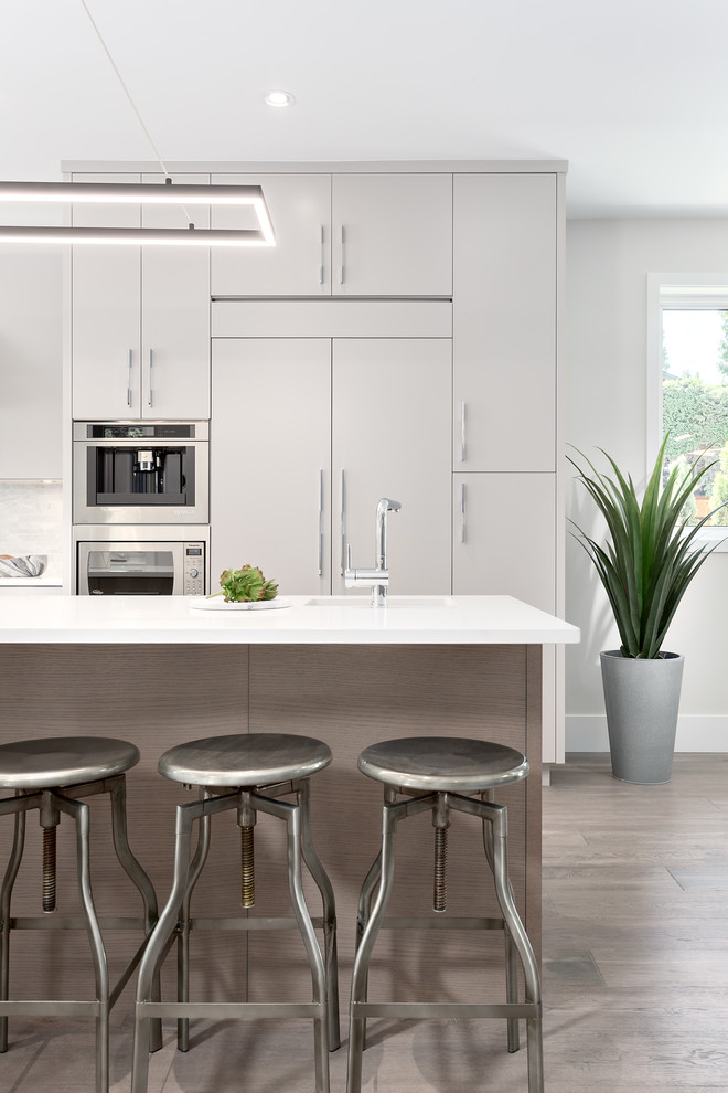 Exempel på ett mellanstort modernt vit vitt kök, med en dubbel diskho, släta luckor, grå skåp, stänkskydd i stenkakel, integrerade vitvaror, mellanmörkt trägolv, en köksö, brunt golv, bänkskiva i koppar och vitt stänkskydd