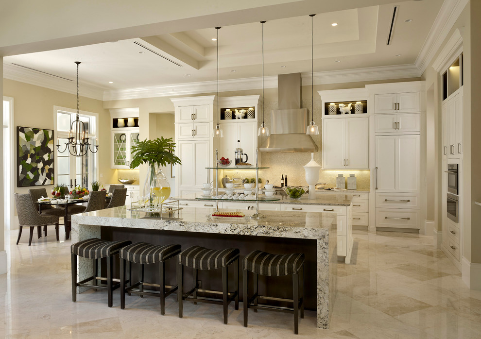 Mediterranean galley kitchen in Miami with recessed-panel cabinets, white cabinets, beige splashback, integrated appliances, an island and beige floors.