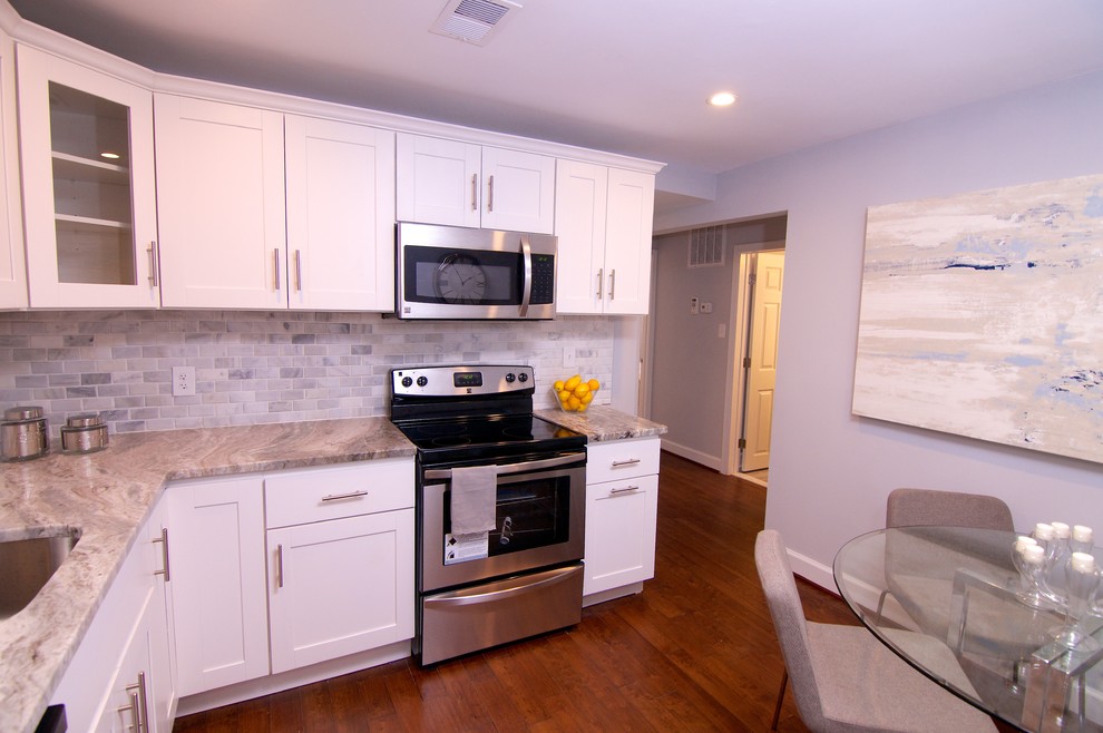 Exempel på ett avskilt, litet modernt l-kök, med en dubbel diskho, skåp i shakerstil, vita skåp, granitbänkskiva, grått stänkskydd, stänkskydd i stenkakel, rostfria vitvaror och mellanmörkt trägolv