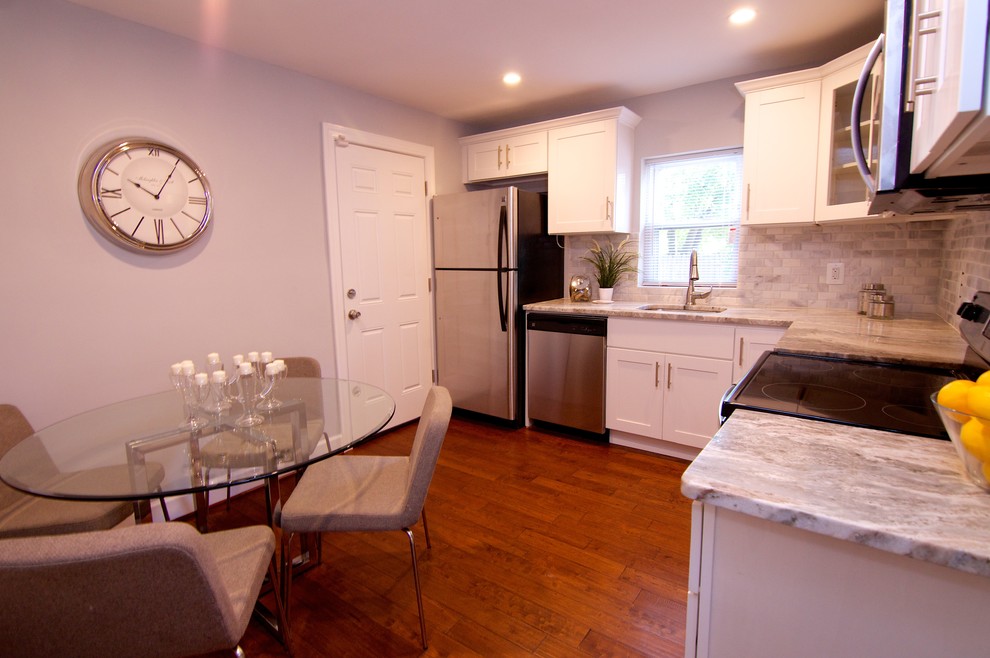 Small minimalist l-shaped medium tone wood floor enclosed kitchen photo in DC Metro with a double-bowl sink, shaker cabinets, white cabinets, granite countertops, gray backsplash, stone tile backsplash and stainless steel appliances