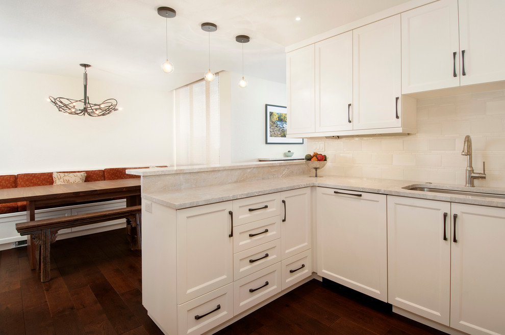 Inspiration for a large traditional u-shaped kitchen/diner in Seattle with a submerged sink, shaker cabinets, white cabinets, marble worktops, white splashback, metro tiled splashback, integrated appliances, dark hardwood flooring and a breakfast bar.