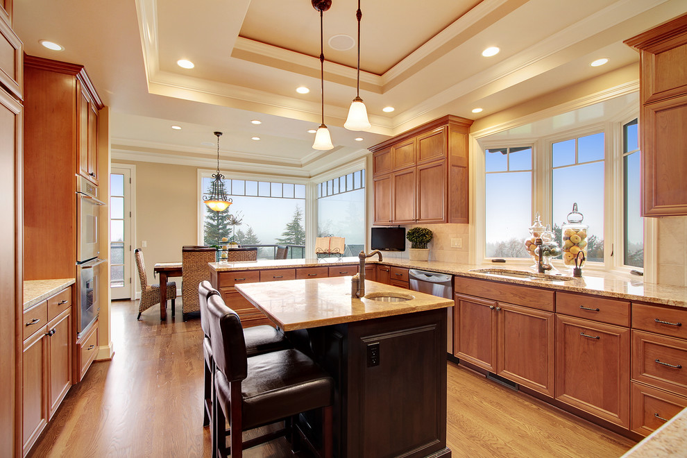 Elegant u-shaped medium tone wood floor eat-in kitchen photo in Seattle with an undermount sink, recessed-panel cabinets, medium tone wood cabinets, beige backsplash, stainless steel appliances and an island