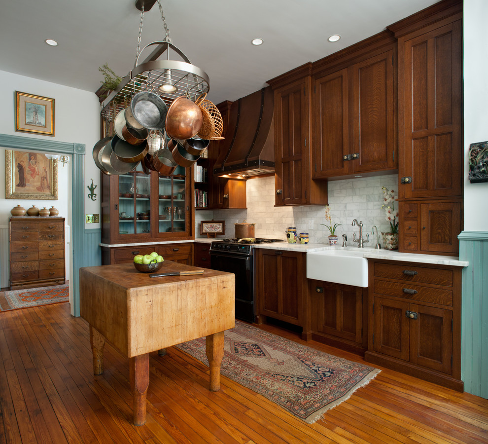 Exempel på ett mellanstort klassiskt l-kök, med en rustik diskho, luckor med infälld panel, skåp i mörkt trä, vitt stänkskydd, stänkskydd i stenkakel, mellanmörkt trägolv, en köksö och brunt golv