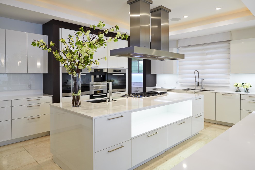 Exempel på ett modernt u-kök, med en undermonterad diskho, släta luckor, vita skåp, vitt stänkskydd, glaspanel som stänkskydd, rostfria vitvaror och en köksö