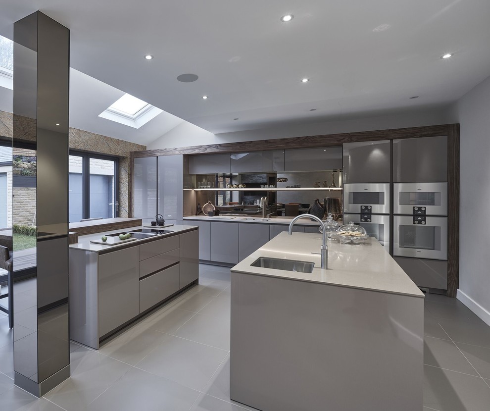 Large contemporary single-wall kitchen/diner in Other with a built-in sink, flat-panel cabinets, beige cabinets, quartz worktops, brown splashback, mirror splashback, stainless steel appliances, porcelain flooring, multiple islands and grey floors.