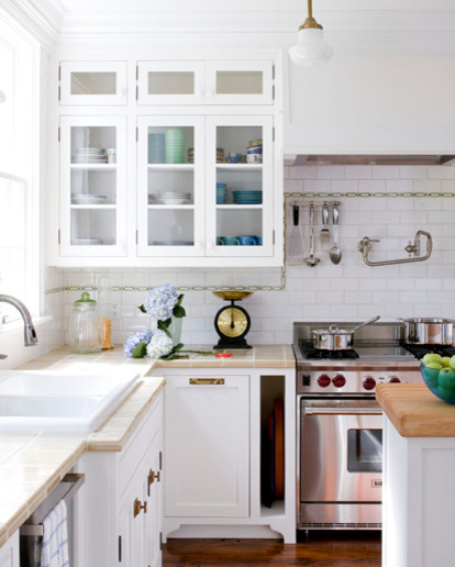 Enclosed kitchen - mid-sized coastal l-shaped medium tone wood floor enclosed kitchen idea in Boston with a drop-in sink, beaded inset cabinets, white cabinets, tile countertops, white backsplash, subway tile backsplash, stainless steel appliances and an island