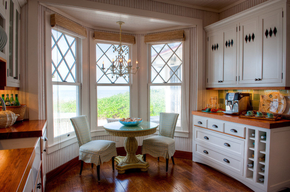 Example of a mid-sized island style galley dark wood floor and brown floor eat-in kitchen design in Miami with wood countertops, a farmhouse sink, shaker cabinets, white cabinets, green backsplash, glass tile backsplash and no island