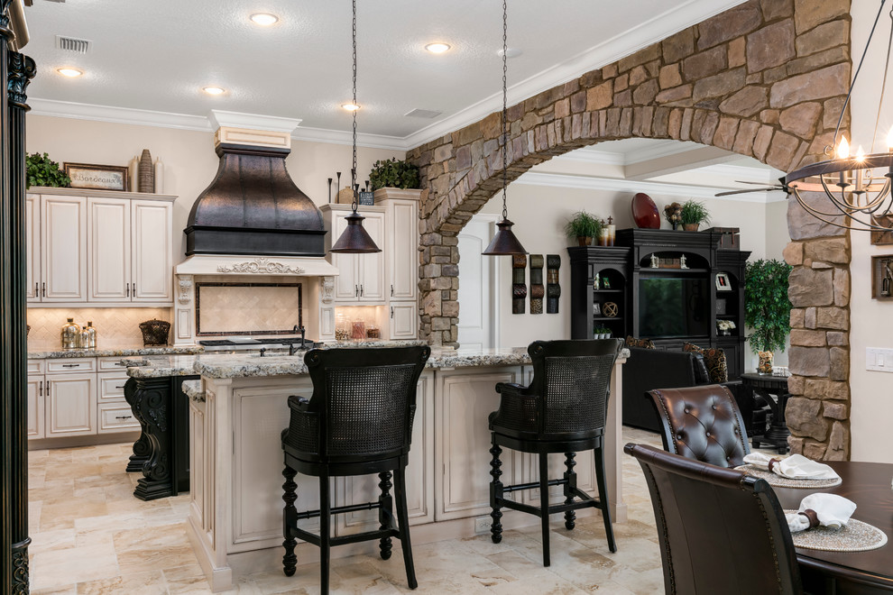 Inspiration for a large mediterranean l-shaped travertine floor eat-in kitchen remodel in Orlando with raised-panel cabinets, white cabinets, granite countertops, beige backsplash, two islands, an undermount sink and black appliances