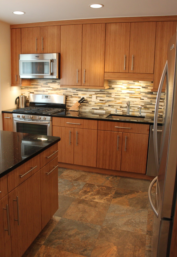 Inredning av ett modernt avskilt, mellanstort l-kök, med en undermonterad diskho, släta luckor, skåp i mellenmörkt trä, granitbänkskiva, flerfärgad stänkskydd, stänkskydd i glaskakel, rostfria vitvaror, klinkergolv i porslin och en köksö
