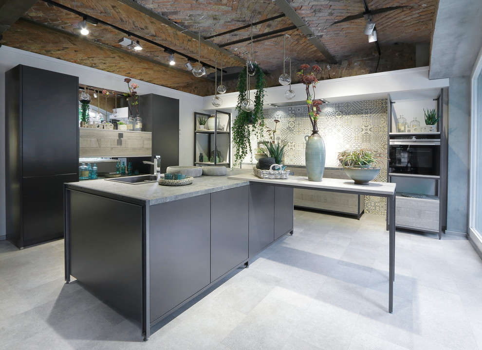 Immagine di un grande cucina con isola centrale eclettico con lavello da incasso, ante lisce, ante nere, top in cemento, paraspruzzi a specchio e elettrodomestici neri