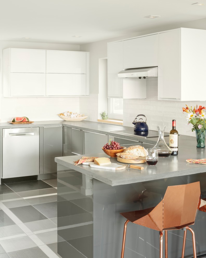 Cette image montre une cuisine ouverte traditionnelle en U et inox de taille moyenne avec un placard à porte plane, une péninsule, une crédence blanche, un électroménager en acier inoxydable et un sol gris.