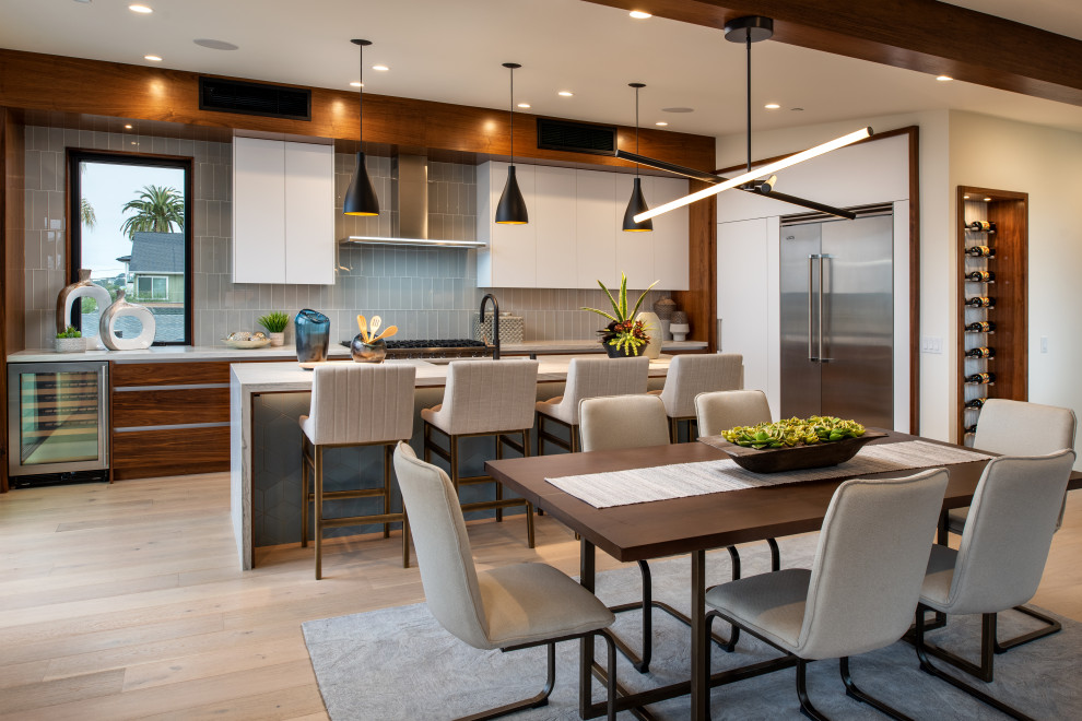 Example of a mid-sized minimalist l-shaped light wood floor and white floor eat-in kitchen design in San Diego with an undermount sink, flat-panel cabinets, medium tone wood cabinets, quartz countertops, gray backsplash, porcelain backsplash, stainless steel appliances, an island and white countertops