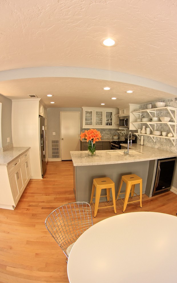 Modern inredning av ett mellanstort kök, med en integrerad diskho, luckor med infälld panel, grå skåp, marmorbänkskiva, vitt stänkskydd, stänkskydd i keramik, rostfria vitvaror och mellanmörkt trägolv