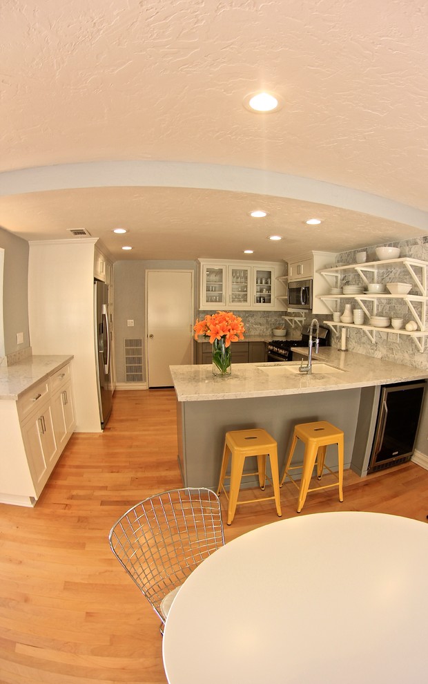 Photo of a medium sized contemporary l-shaped open plan kitchen in San Diego with an integrated sink, recessed-panel cabinets, grey cabinets, marble worktops, white splashback, ceramic splashback, stainless steel appliances, medium hardwood flooring and no island.