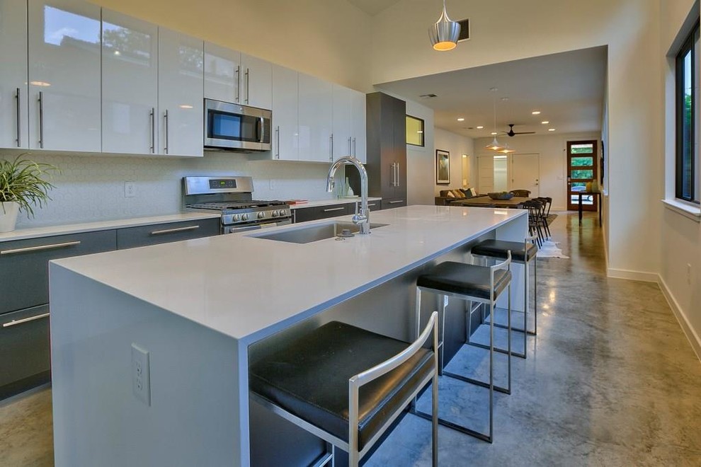 This is an example of a large contemporary galley kitchen in Austin with a submerged sink, flat-panel cabinets, grey cabinets, engineered stone countertops, stainless steel appliances, concrete flooring, an island and grey floors.