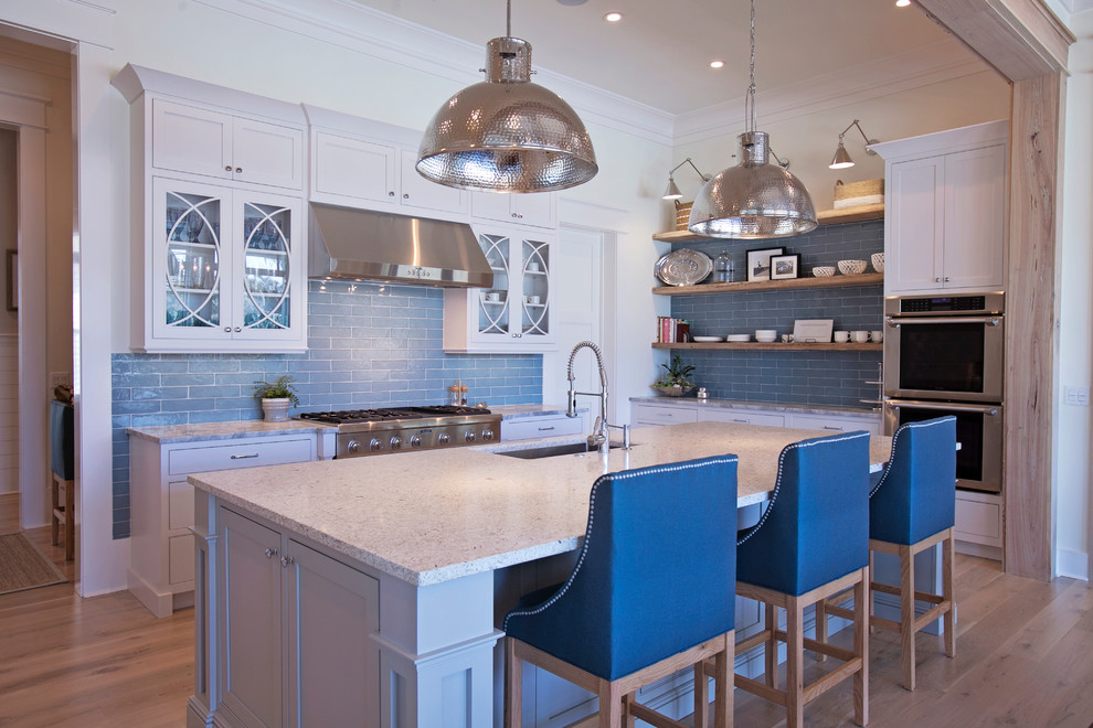Photo of a large classic l-shaped kitchen/diner in Atlanta with a submerged sink, shaker cabinets, white cabinets, engineered stone countertops, blue splashback, metro tiled splashback, integrated appliances, medium hardwood flooring and an island.