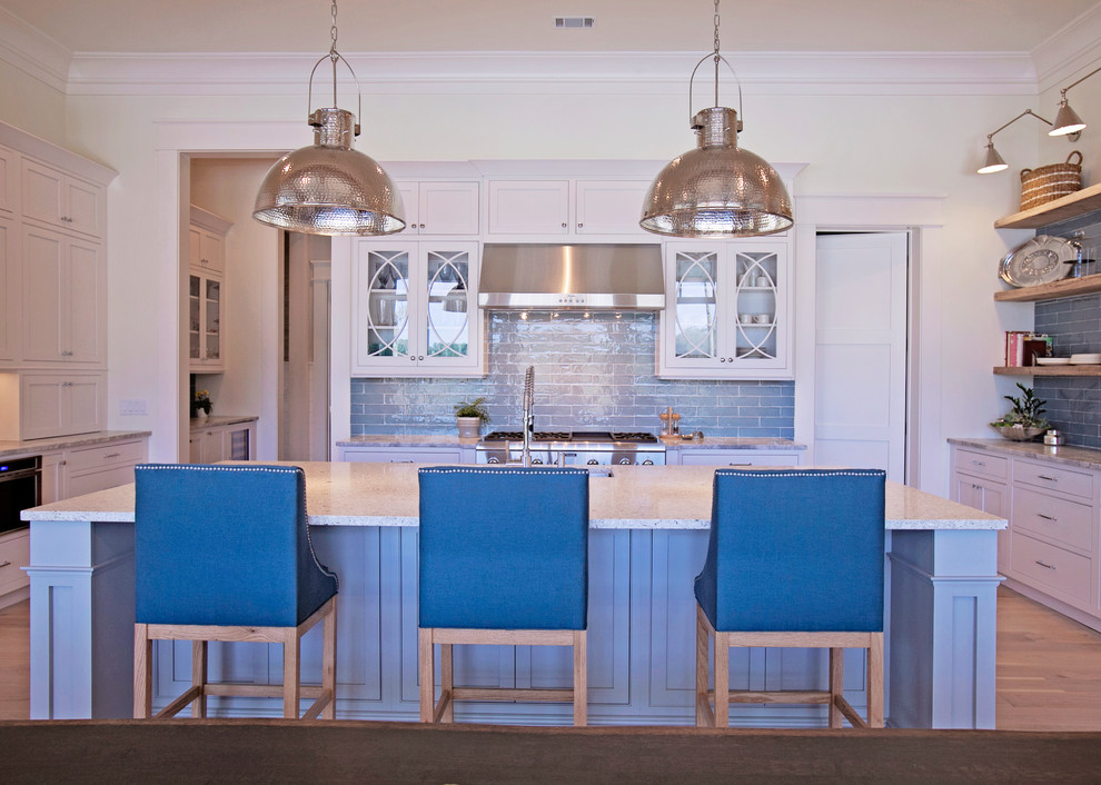 This is an example of a large classic l-shaped kitchen/diner in Atlanta with a submerged sink, shaker cabinets, white cabinets, engineered stone countertops, blue splashback, metro tiled splashback, integrated appliances, medium hardwood flooring and an island.