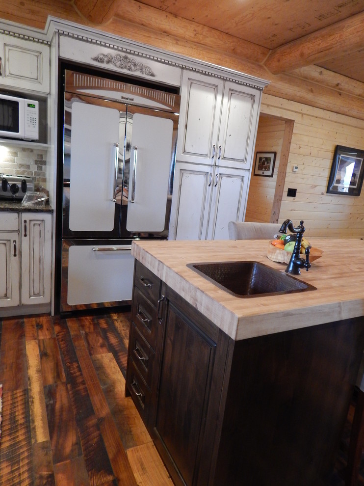 Rustikale Küche mit profilierten Schrankfronten, Schränken im Used-Look, Granit-Arbeitsplatte, Küchenrückwand in Beige, bunten Elektrogeräten, Landhausspüle und dunklem Holzboden in Vancouver