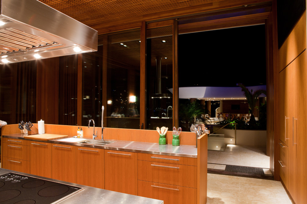 Cette image montre une très grande cuisine ouverte parallèle ethnique en bois clair avec un placard à porte plane, un électroménager en acier inoxydable et îlot.