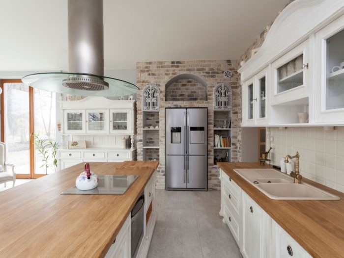 Inspiration for a mid-sized craftsman galley concrete floor and gray floor eat-in kitchen remodel in Other with a drop-in sink, recessed-panel cabinets, white cabinets, wood countertops, white backsplash, ceramic backsplash, stainless steel appliances and an island
