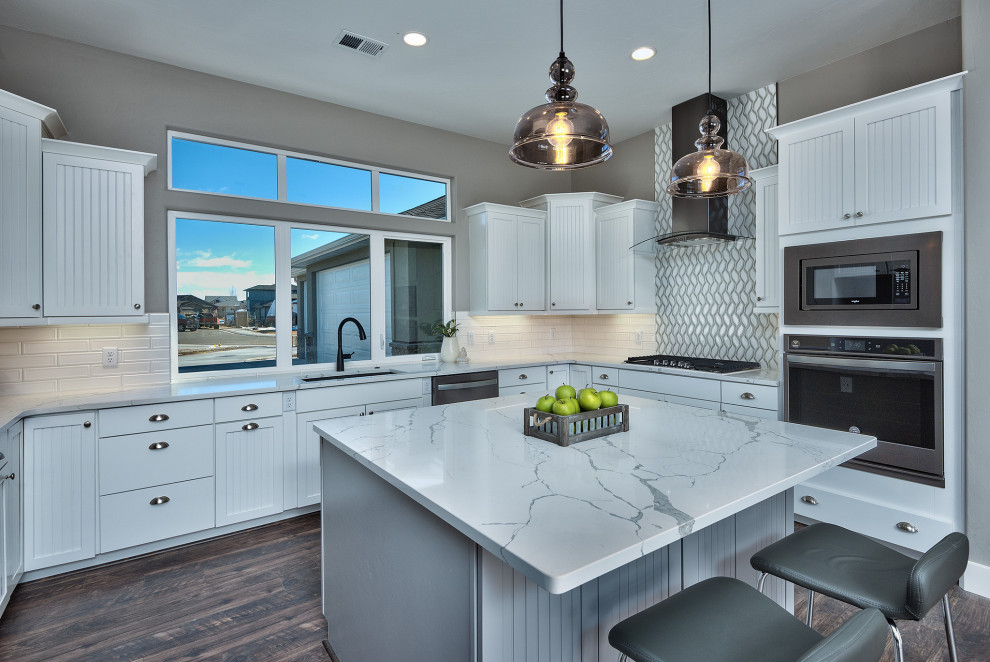 Large trendy u-shaped medium tone wood floor and multicolored floor open concept kitchen photo in Other with an undermount sink, recessed-panel cabinets, white cabinets, laminate countertops, white backsplash, ceramic backsplash, stainless steel appliances, an island and white countertops