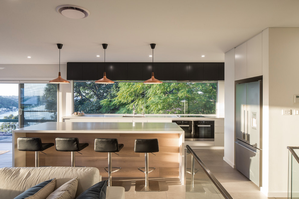 Offene Moderne Küche in L-Form mit Unterbauwaschbecken, flächenbündigen Schrankfronten, schwarzen Schränken, Rückwand-Fenster, Küchengeräten aus Edelstahl, Kücheninsel und beigem Boden in Sydney