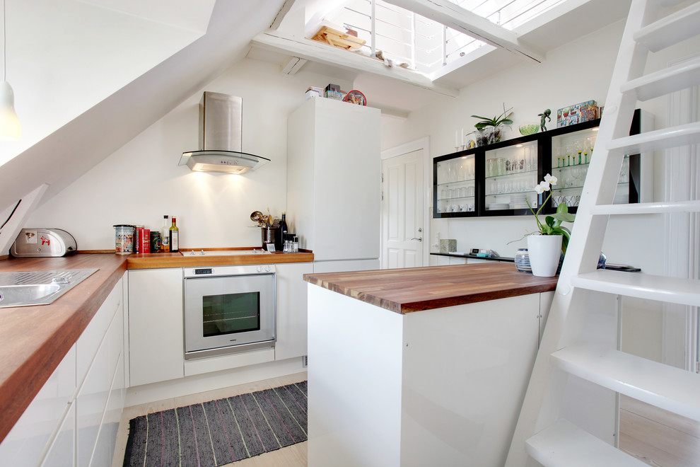 Photo of a small scandinavian kitchen in Copenhagen with glass-front cabinets, white cabinets, white splashback, white appliances, light hardwood flooring and a breakfast bar.