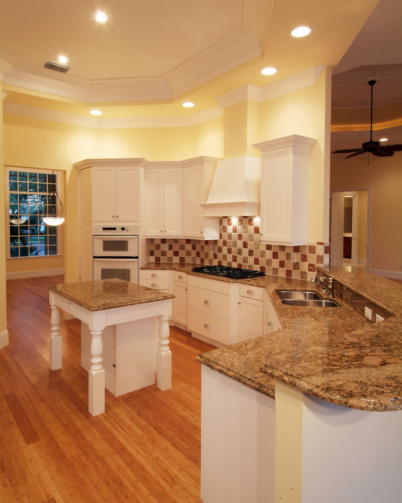 Cette image montre une cuisine marine avec un plan de travail en granite, une crédence multicolore et parquet clair.