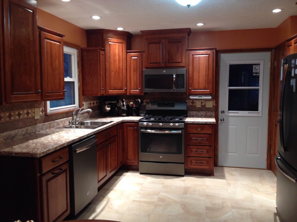 Example of a small country u-shaped enclosed kitchen design in Chicago with a double-bowl sink, raised-panel cabinets, brown cabinets, brown backsplash, ceramic backsplash, stainless steel appliances and no island