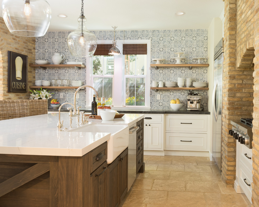 Bild på ett stort lantligt kök, med en rustik diskho, luckor med infälld panel, vita skåp, bänkskiva i kvartsit, blått stänkskydd, stänkskydd i cementkakel, rostfria vitvaror, travertin golv, en köksö och beiget golv