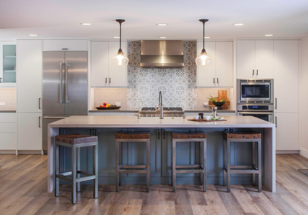 Example of a large transitional galley vinyl floor and gray floor open concept kitchen design in Denver with flat-panel cabinets, gray cabinets, a farmhouse sink, beige backsplash, subway tile backsplash, stainless steel appliances, an island and gray countertops