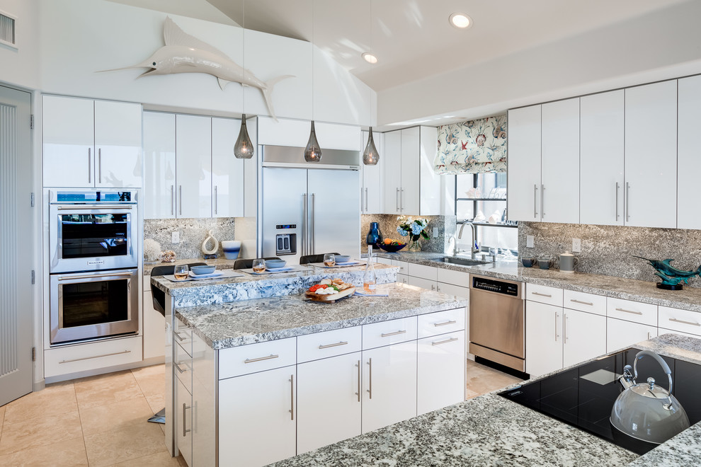 Inspiration for a medium sized beach style u-shaped kitchen in San Diego with a submerged sink, flat-panel cabinets, white cabinets, granite worktops, grey splashback, stainless steel appliances, porcelain flooring, an island, beige floors and grey worktops.