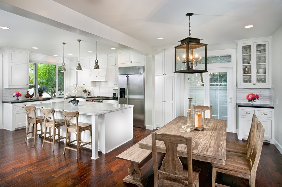 Elegant l-shaped eat-in kitchen photo in San Diego with a farmhouse sink, white cabinets, marble countertops, white backsplash, subway tile backsplash and stainless steel appliances