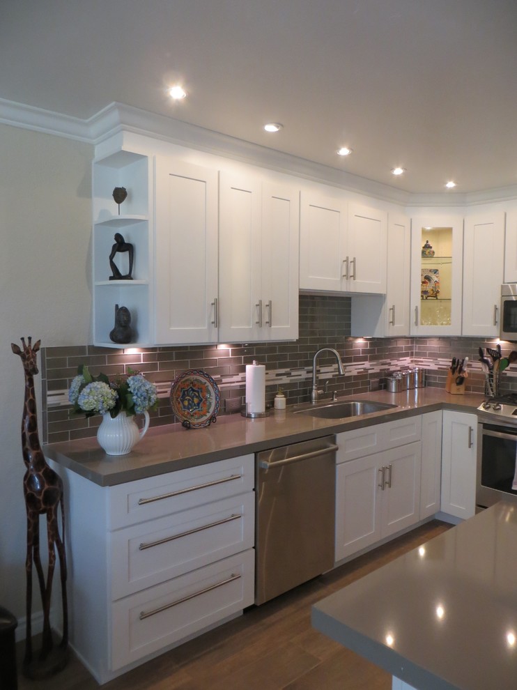 Photo of a large contemporary l-shaped kitchen/diner in San Diego with a submerged sink, shaker cabinets, white cabinets, quartz worktops, grey splashback, metro tiled splashback, stainless steel appliances, porcelain flooring and an island.