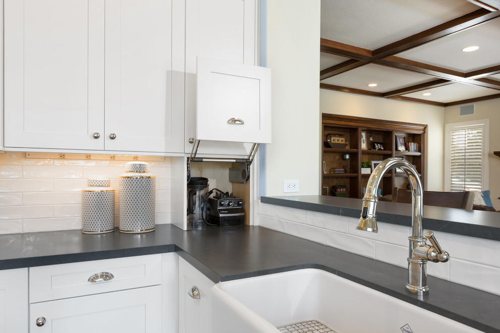 Inspiration for a large traditional u-shaped kitchen pantry in Tampa with a belfast sink, shaker cabinets, white cabinets, soapstone worktops, white splashback, metro tiled splashback, stainless steel appliances, dark hardwood flooring, an island, brown floors and grey worktops.