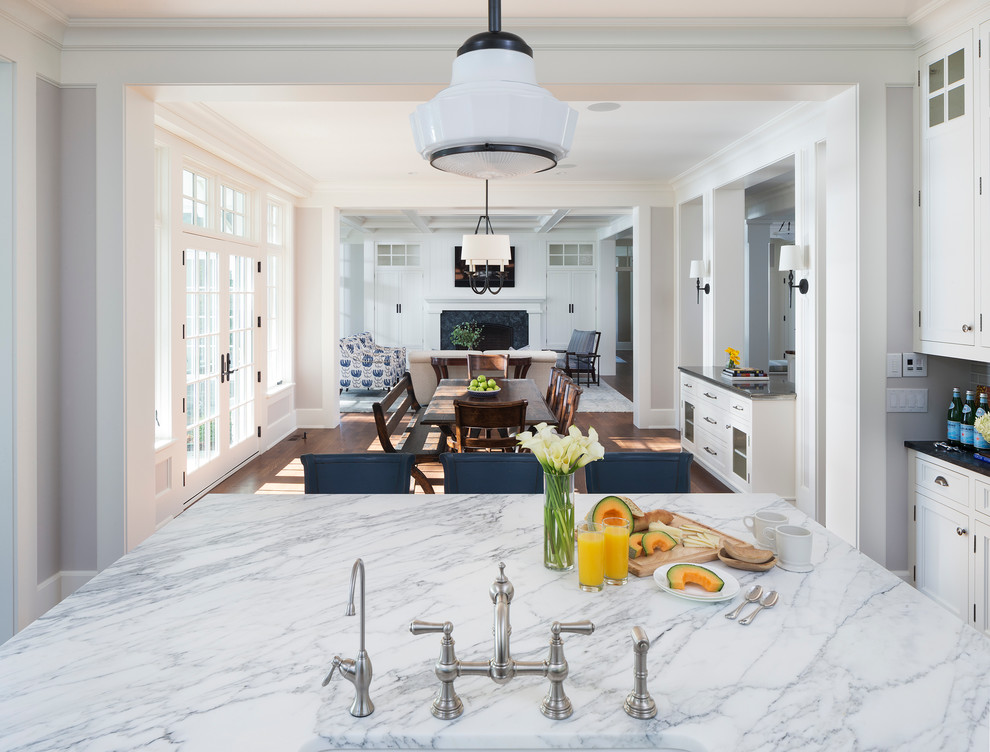 Klassisk inredning av ett kök och matrum, med en rustik diskho, vita skåp, marmorbänkskiva, grått stänkskydd, stänkskydd i keramik, integrerade vitvaror, mellanmörkt trägolv och en köksö