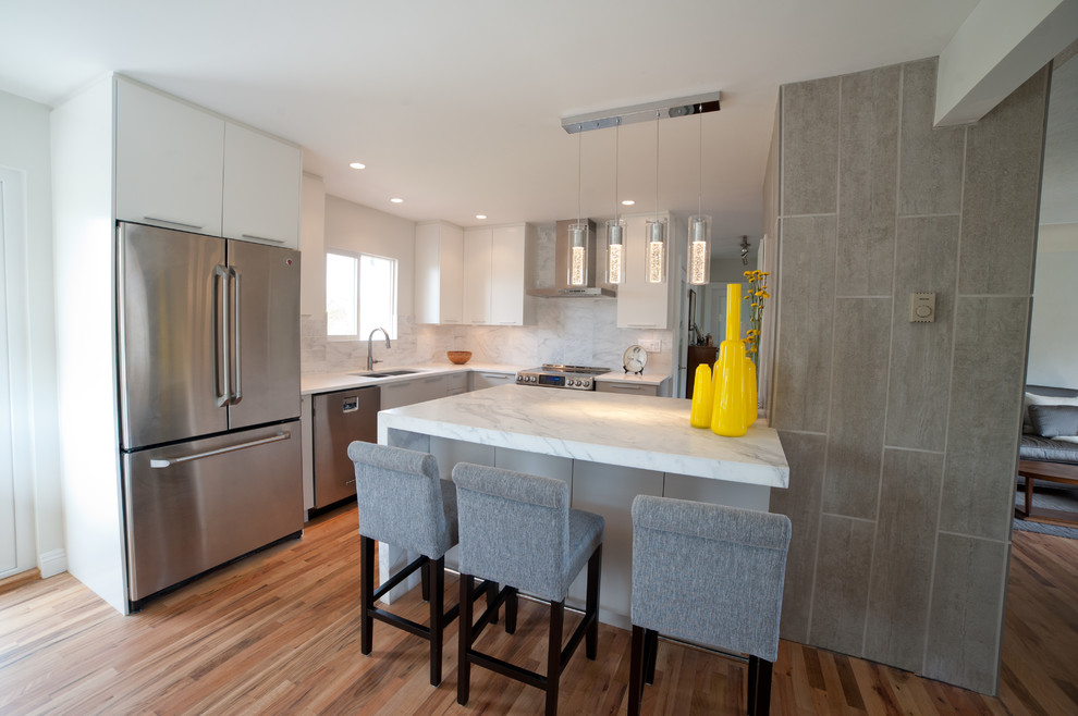 Modern inredning av ett avskilt, mellanstort u-kök, med en undermonterad diskho, släta luckor, grå skåp, marmorbänkskiva, flerfärgad stänkskydd, stänkskydd i stenkakel, rostfria vitvaror, mellanmörkt trägolv, en köksö och brunt golv