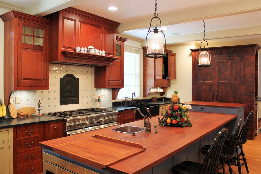 Eat-in kitchen - large traditional u-shaped medium tone wood floor eat-in kitchen idea in Indianapolis with a farmhouse sink, soapstone countertops, white backsplash, paneled appliances and an island