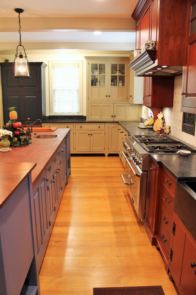 Modelo de cocina tradicional grande con fregadero sobremueble, encimera de esteatita, salpicadero blanco, electrodomésticos con paneles, suelo de madera en tonos medios y una isla