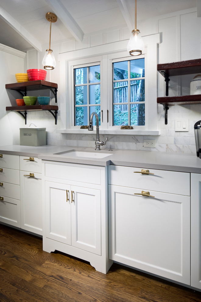 Example of a mid-sized transitional galley dark wood floor and brown floor eat-in kitchen design in Other with recessed-panel cabinets, white cabinets, stainless steel appliances, no island, an undermount sink, solid surface countertops, white backsplash and marble backsplash