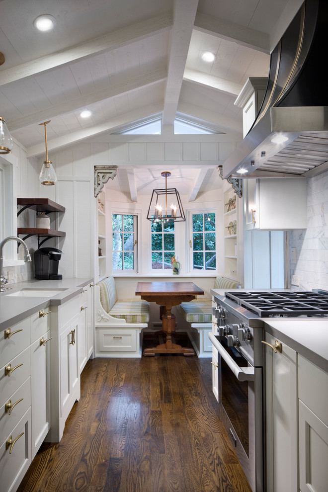 Klassisk inredning av ett mellanstort kök, med luckor med infälld panel, vita skåp, rostfria vitvaror, mörkt trägolv, en undermonterad diskho, bänkskiva i koppar, vitt stänkskydd, stänkskydd i marmor och brunt golv