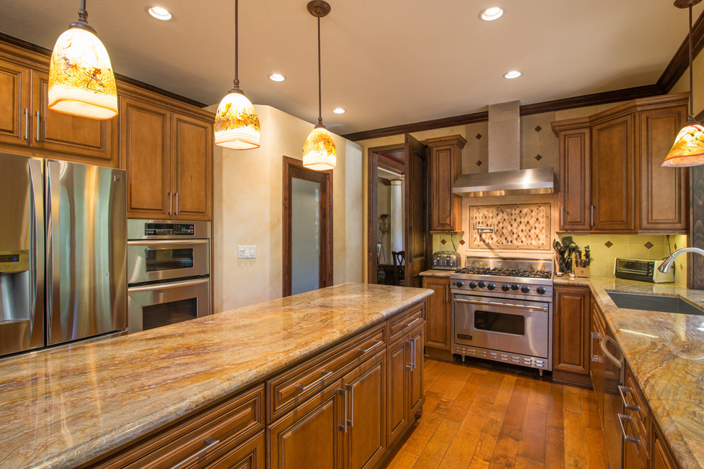 Inspiration for a large mediterranean u-shaped medium tone wood floor enclosed kitchen remodel in San Diego with a drop-in sink, recessed-panel cabinets, medium tone wood cabinets, granite countertops, beige backsplash, terra-cotta backsplash, stainless steel appliances and an island