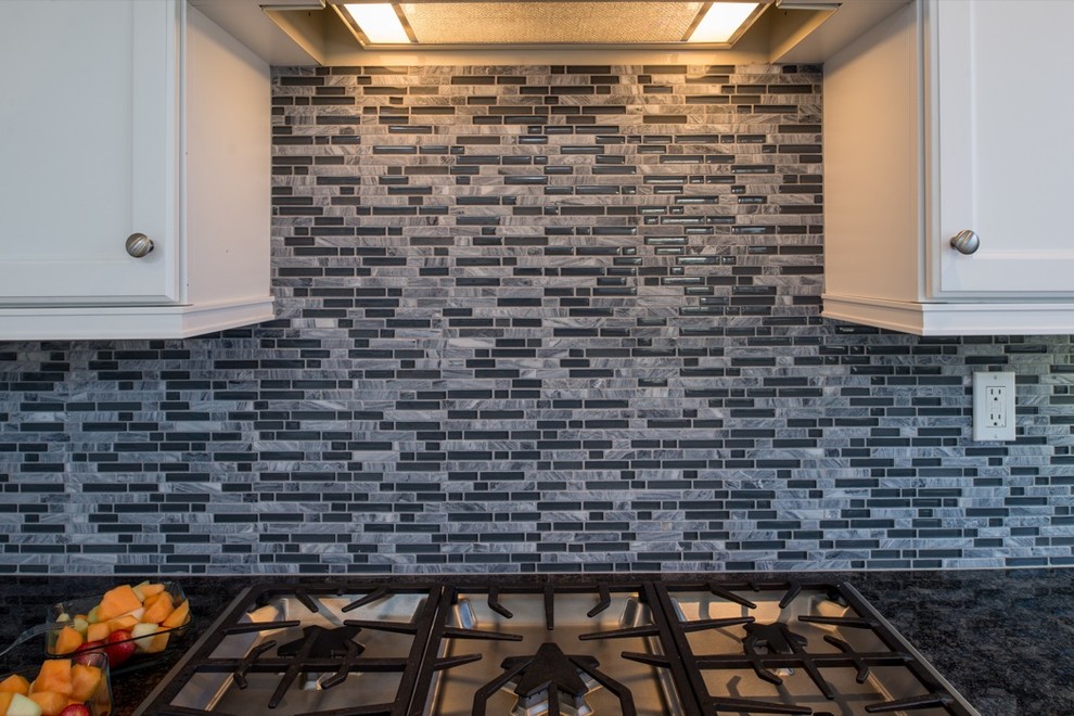 Exempel på ett klassiskt kök, med en nedsänkt diskho, luckor med infälld panel, vita skåp, granitbänkskiva, flerfärgad stänkskydd och rostfria vitvaror