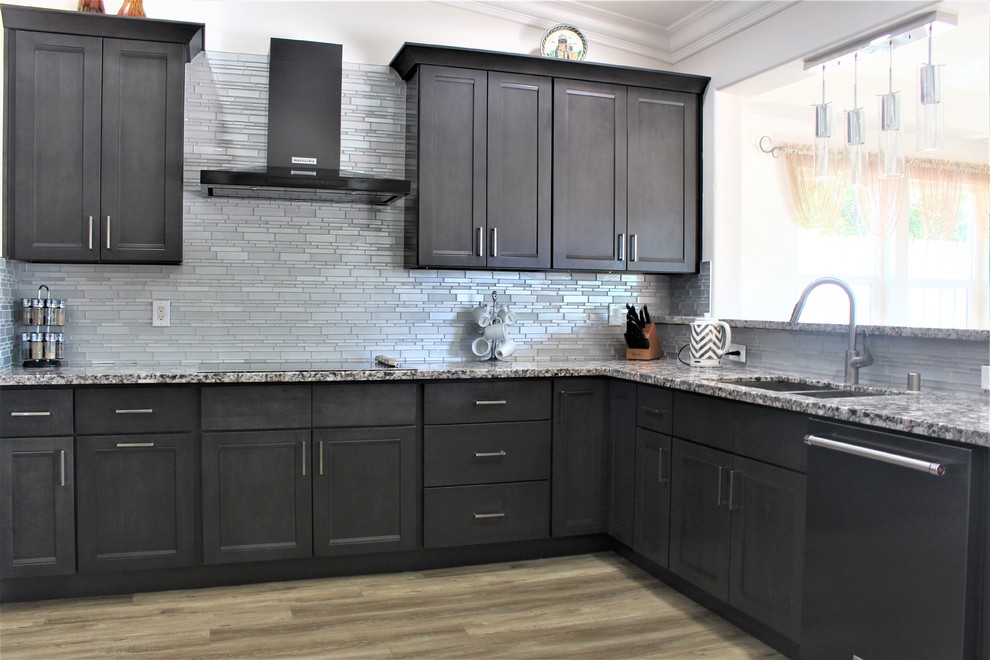This is an example of a large contemporary u-shaped open plan kitchen in Sacramento with a submerged sink, shaker cabinets, grey cabinets, granite worktops, grey splashback, glass tiled splashback, black appliances, light hardwood flooring, no island and beige floors.