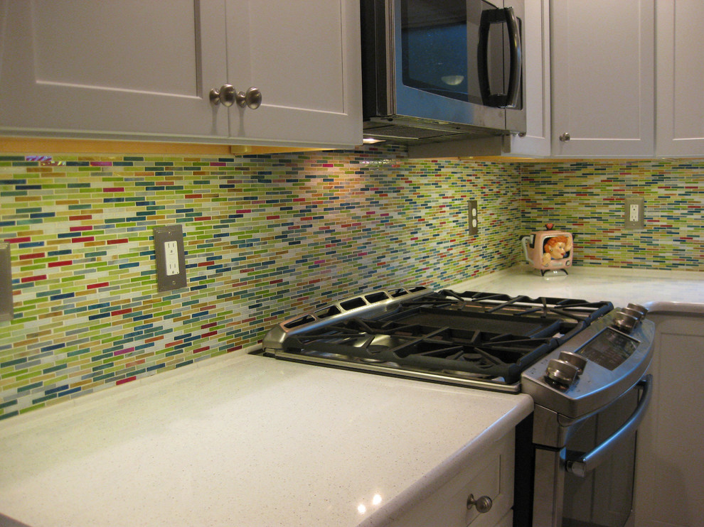 Inredning av ett modernt mellanstort kök, med vita skåp, flerfärgad stänkskydd, stänkskydd i glaskakel och rostfria vitvaror