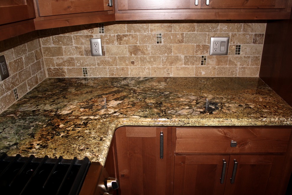Cette image montre une cuisine américaine parallèle traditionnelle avec un évier encastré, un plan de travail en granite, une crédence marron, une crédence en carrelage de pierre et un placard à porte shaker.