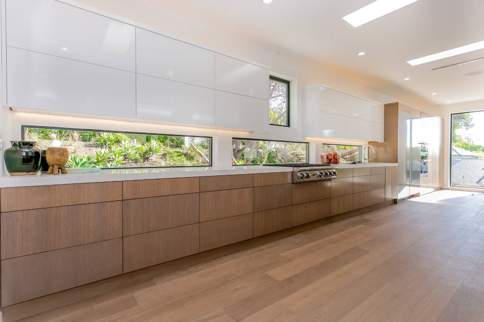 Eat-in kitchen - huge contemporary galley medium tone wood floor eat-in kitchen idea in Los Angeles with an undermount sink, flat-panel cabinets, medium tone wood cabinets, solid surface countertops, stainless steel appliances and an island