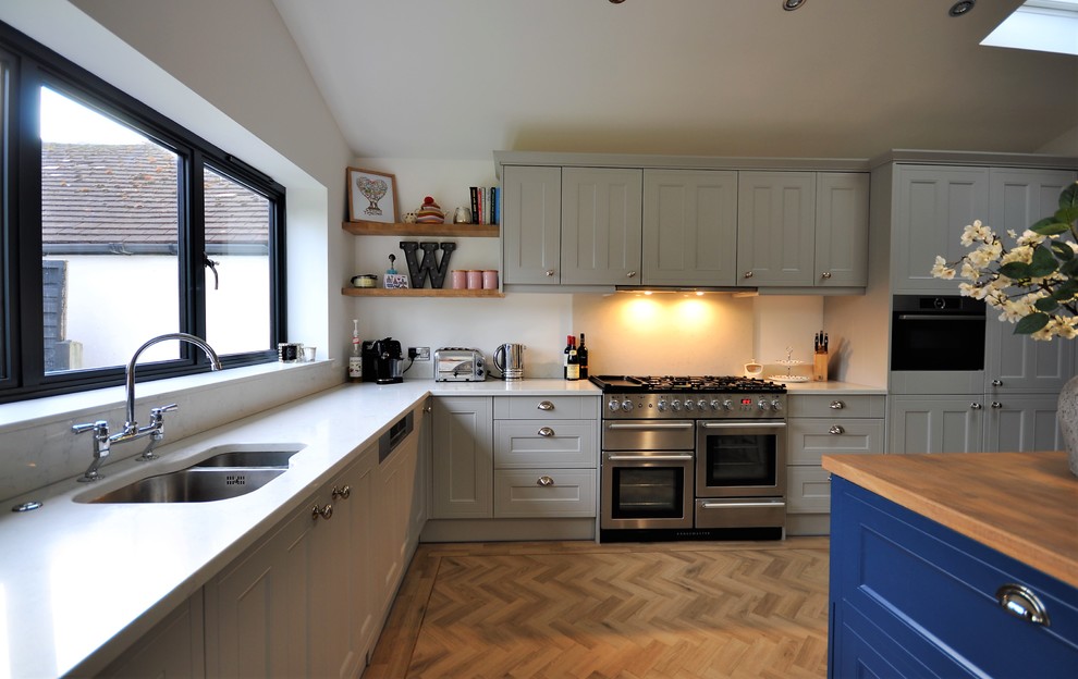 Immagine di una cucina minimalista di medie dimensioni con ante in stile shaker, ante grigie, top in quarzite, paraspruzzi bianco, paraspruzzi in lastra di pietra, elettrodomestici in acciaio inossidabile e top bianco