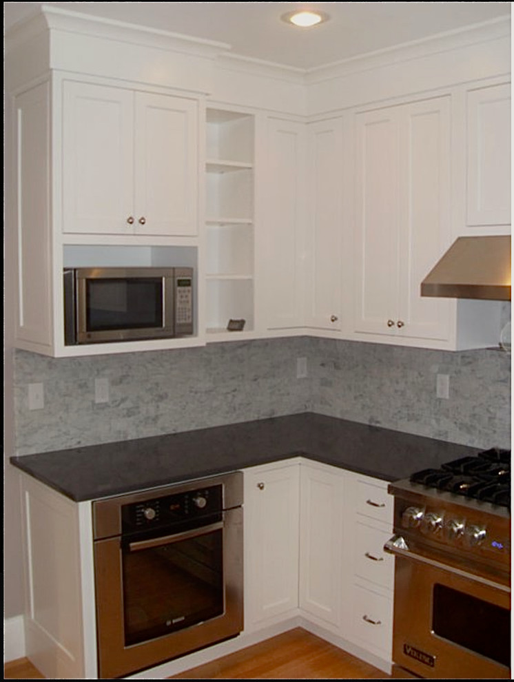 Eat-in kitchen - mid-sized traditional l-shaped medium tone wood floor eat-in kitchen idea in Providence with a peninsula, shaker cabinets, white cabinets, quartz countertops, gray backsplash, porcelain backsplash, stainless steel appliances and an undermount sink